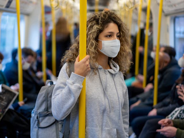 <p>Stock photo of woman wearing a facemask on public transport </p>